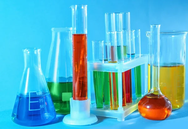 Vidros químicos com amostras coloridas sobre fundo de cor — Fotografia de Stock