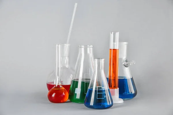 Chemical glassware with colorful samples on color background — Stock Photo, Image