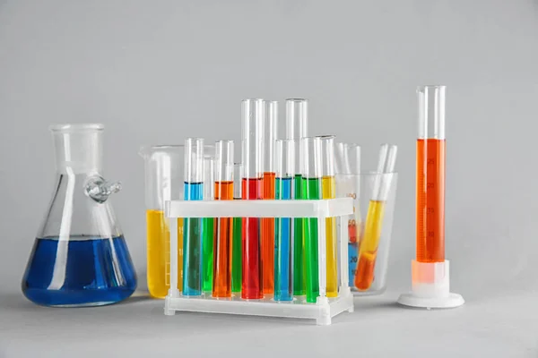 Cristalería química con muestras coloridas sobre fondo de color — Foto de Stock