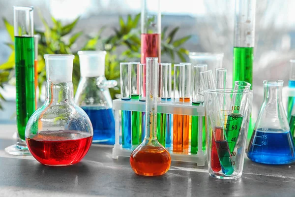 Cristalería química con muestras coloridas en la mesa — Foto de Stock