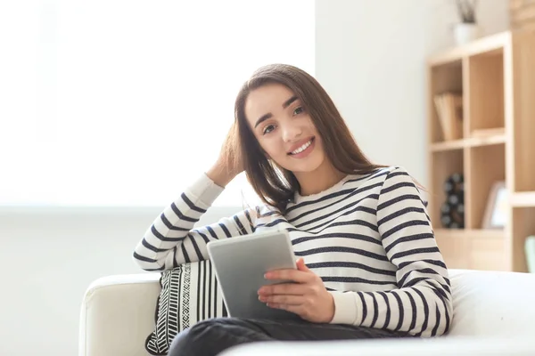 Giovane donna che utilizza tablet mentre si riposa sul divano a casa — Foto Stock