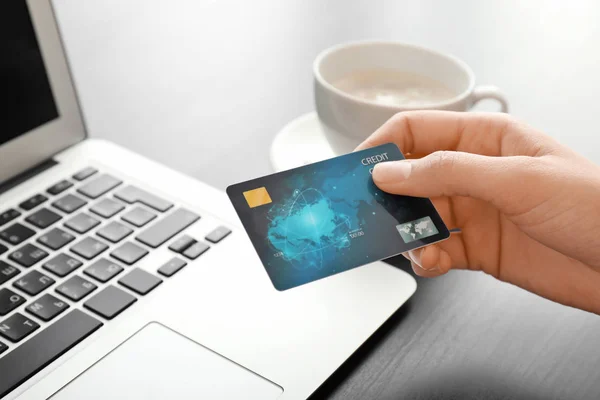 Jovem com cartão de crédito usando laptop na mesa — Fotografia de Stock