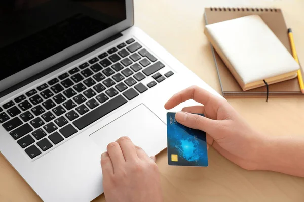 Junge Frau mit Kreditkarte mit Laptop am Tisch — Stockfoto