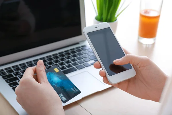 Jonge vrouw met creditcard via smartphone aan tafel — Stockfoto