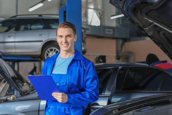 Male mechanic with clipboard near car in service center — Stock Photo, Image