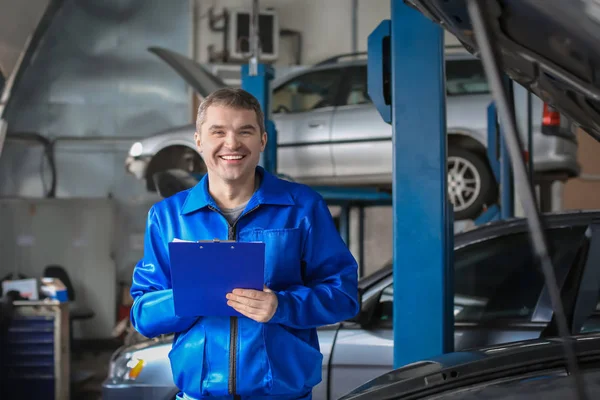 Male mechanic with clipboard near car in service center — Stock Photo, Image