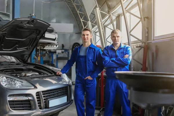 Retrato de los mecánicos masculinos cerca del coche en el centro de servicio — Foto de Stock