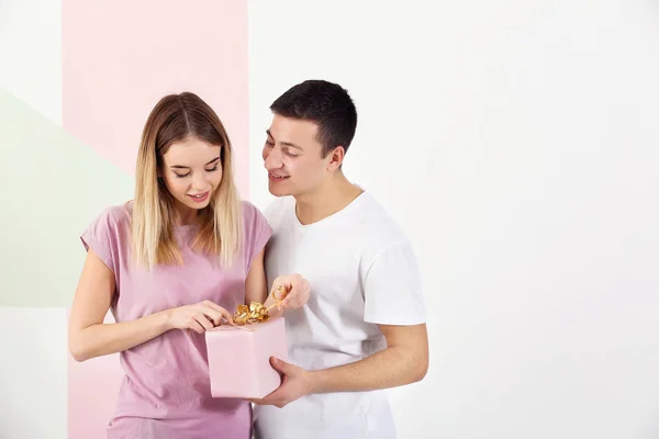 Young woman opening gift box from her boyfriend on light background — Stock Photo, Image
