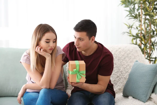 Joven hombre dando regalo a su amada novia en casa — Foto de Stock