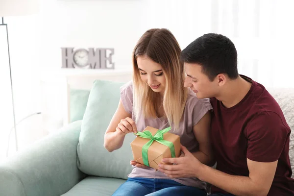 Mujer joven con regalo de su amado novio en casa — Foto de Stock