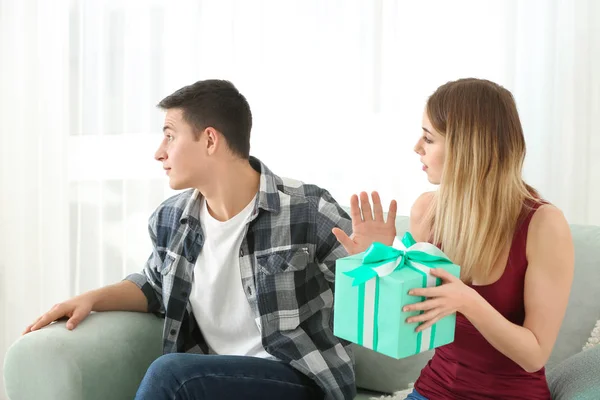 Offended young man refusing to take gift from his girlfriend at home — Stock Photo, Image