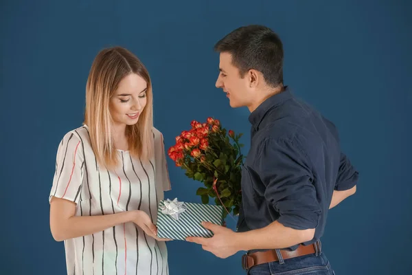 年轻人送礼物和花给他心爱的女朋友在颜色背景 — 图库照片