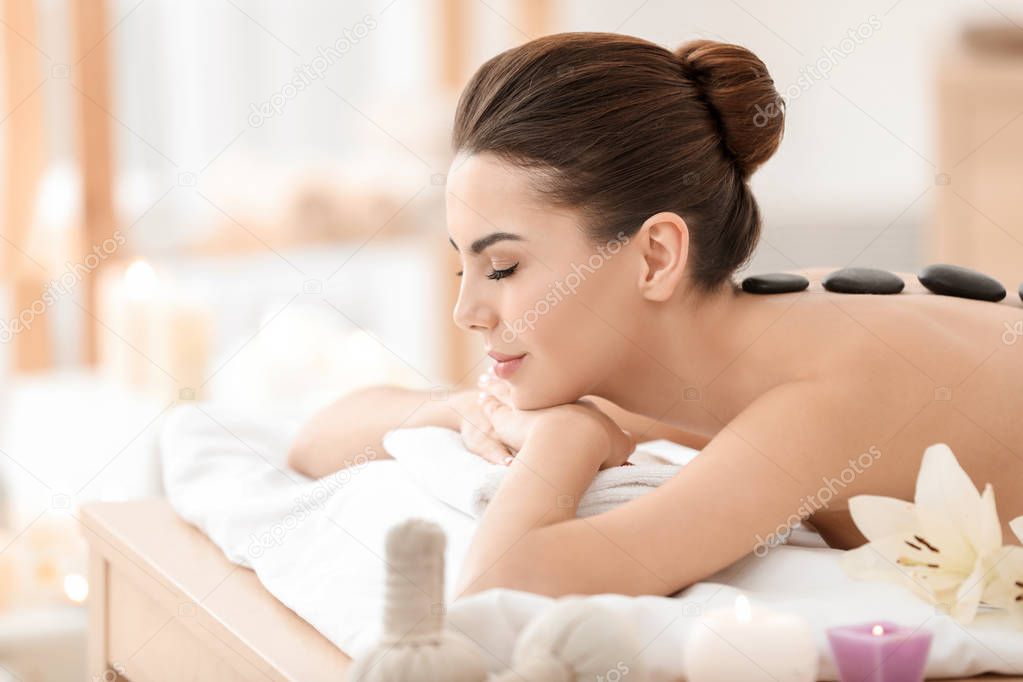 Young woman enjoying stone massage in spa salon