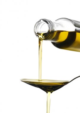 Beyaz zemin üzerine kaşık içine şişe zeytinyağı dökerek kadın