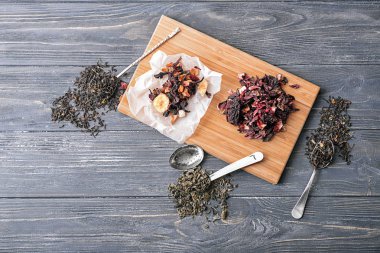 Ahşap arka plan üzerinde kuru çay çeşitleri ile düz yatıyordu kompozisyon