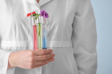 Test tüpleri ile çiçek renk arka plan üzerinde tutan bilim adamı