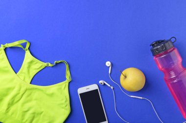 Spor top, smartphone, elma ve şişe su renk arka plan üzerinde düz yatıyordu kompozisyonu. Jimnastik salonu iş