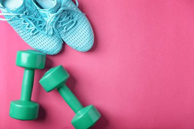 Spor ayakkabı ve dumbell renk arka plan üzerinde düz yatıyordu kompozisyonu. Jimnastik salonu iş