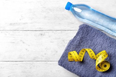 Düz yatıyordu bileşimi şişe ile su, havlu ve ahşap arka plan üzerinde ölçüm bandı. Jimnastik salonu iş
