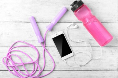 Smartphone, şişe su ve ahşap arka plan üzerinde ip atlama ile düz yatıyordu kompozisyon. Jimnastik salonu iş