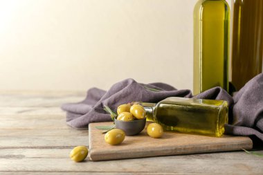 Şişe petrol ve karşı açık renkli ahşap masa üzerinde taze zeytin ile