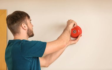 Genç adam Alarm zili duvara yükleme