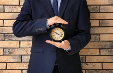 Çalar saat tuğla arka planda tutan adam. Zaman yönetimi kavramı