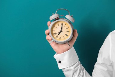 Çalar saat renk arka plan üzerinde tutan adam. Zaman yönetimi kavramı