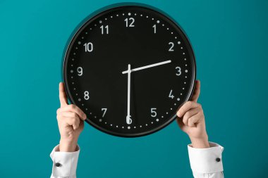 Saat renk arka plan üzerinde tutan adam. Zaman yönetimi kavramı