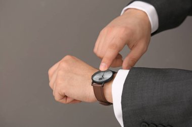 Onun gri arka plan üzerine bakarak adam. Zaman yönetimi kavramı