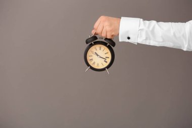 Çalar saat gri arka plan üzerinde tutan adam. Zaman yönetimi kavramı