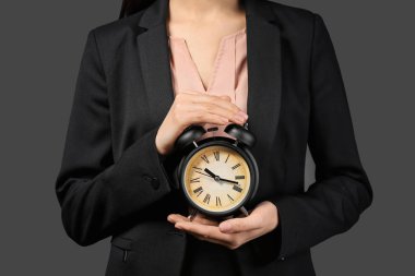 Koyu arka plan üzerinde saat tutan kadın. Zaman yönetimi kavramı