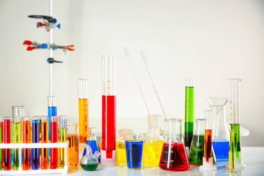 Farklı test tüpleri ve açık renkli karşı masada renkli sıvılar ile Laboratuar kapkacakları