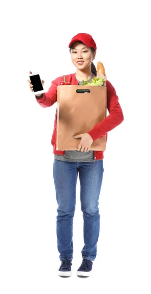 Азиатка с бумажным пакетом и мобильным телефоном на белом фоне. Доставка продуктов питания — стоковое фото