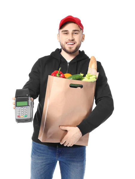 Jovem com produtos em saco de papel e terminal bancário em fundo branco. Serviço de entrega de alimentos — Fotografia de Stock