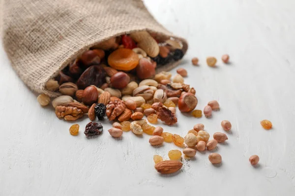 Sackcloth bag with mix of nuts and dried fruits on light background — Stock Photo, Image