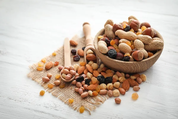 Schaal met diverse smakelijke noten en gedroogde vruchten op houten tafel — Stockfoto
