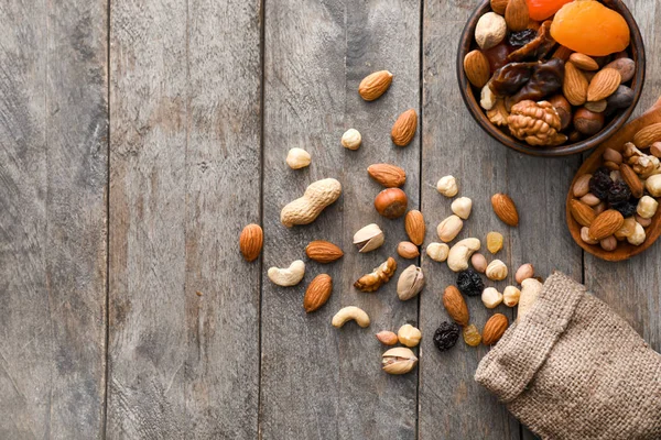 Различные вкусные орехи и сухофрукты на деревянном столе — стоковое фото