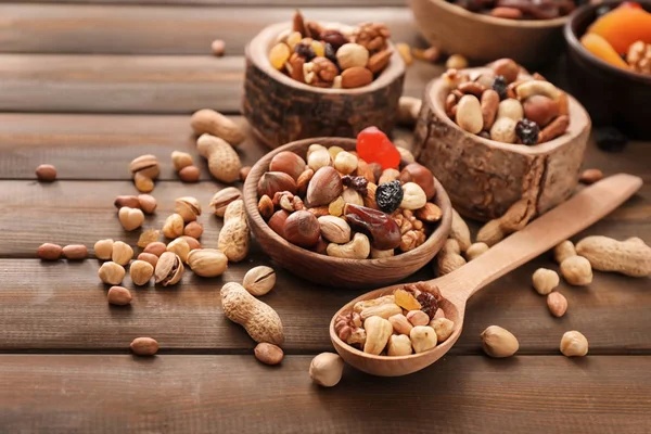 Різні смачні горіхи з мисками і ложкою на дерев'яному столі — стокове фото