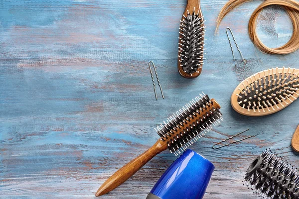 Flat lay composition with hairdresser's tools and strand of blonde hair on wooden background — Stock Photo, Image