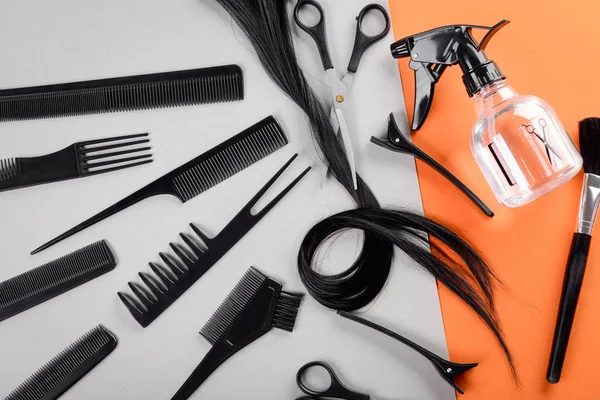 Flat lay composition with hairdresser's tools and strand of black hair on color background — Stock Photo, Image