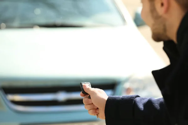 Uomo pulsante sul telecomando del sistema di allarme auto, all'aperto — Foto Stock