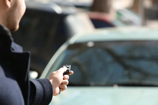 Hombre pulsando el botón en el control remoto del sistema de alarma del coche, al aire libre — Foto de Stock