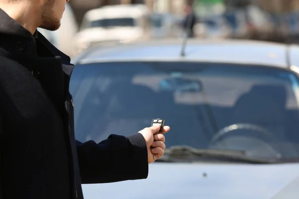 Uomo pulsante sul telecomando del sistema di allarme auto, all'aperto — Foto Stock