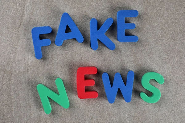 Фраза FAKE NEWS выполнена с цветными буквами на деревянном фоне — стоковое фото