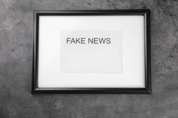 Cadre avec des mots FAKE NEWS sur fond gris — Photo