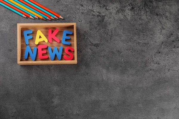 Phrase FAKE NEWS made with color letters in wooden box on gray background — Stock Photo, Image