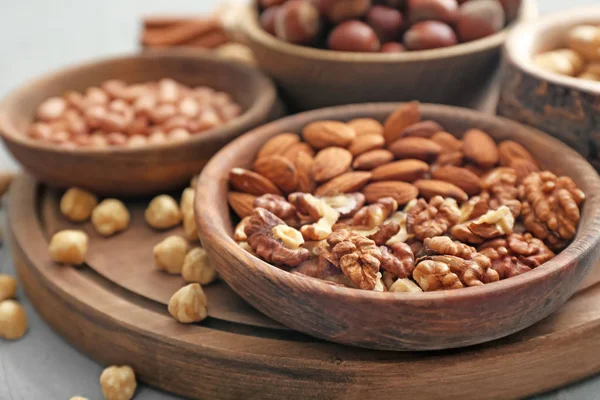 Diferentes tipos de nueces en cuencos en la mesa, primer plano — Foto de Stock