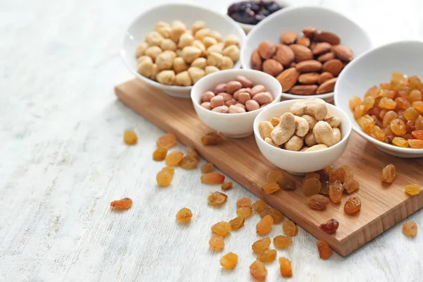 Diferentes tipos de nueces en cuencos y pasas en la mesa — Foto de Stock