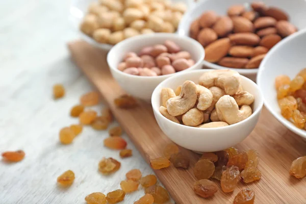 Diferentes tipos de nueces en cuencos y pasas en la mesa, primer plano — Foto de Stock